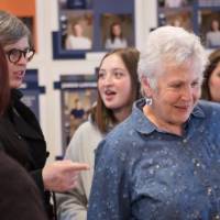 A women smiles while reading a story from the exhibit
